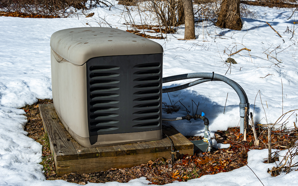 Residential backup generator on a concrete pad in snow