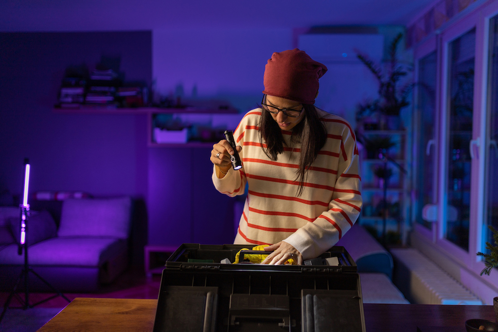 Woman holding a flashlight looking for tools during a power outage, in need of generator installs.