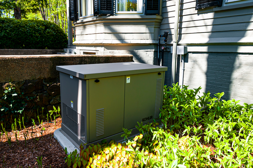 Residential standby generator surrounded by green. | Generator Services